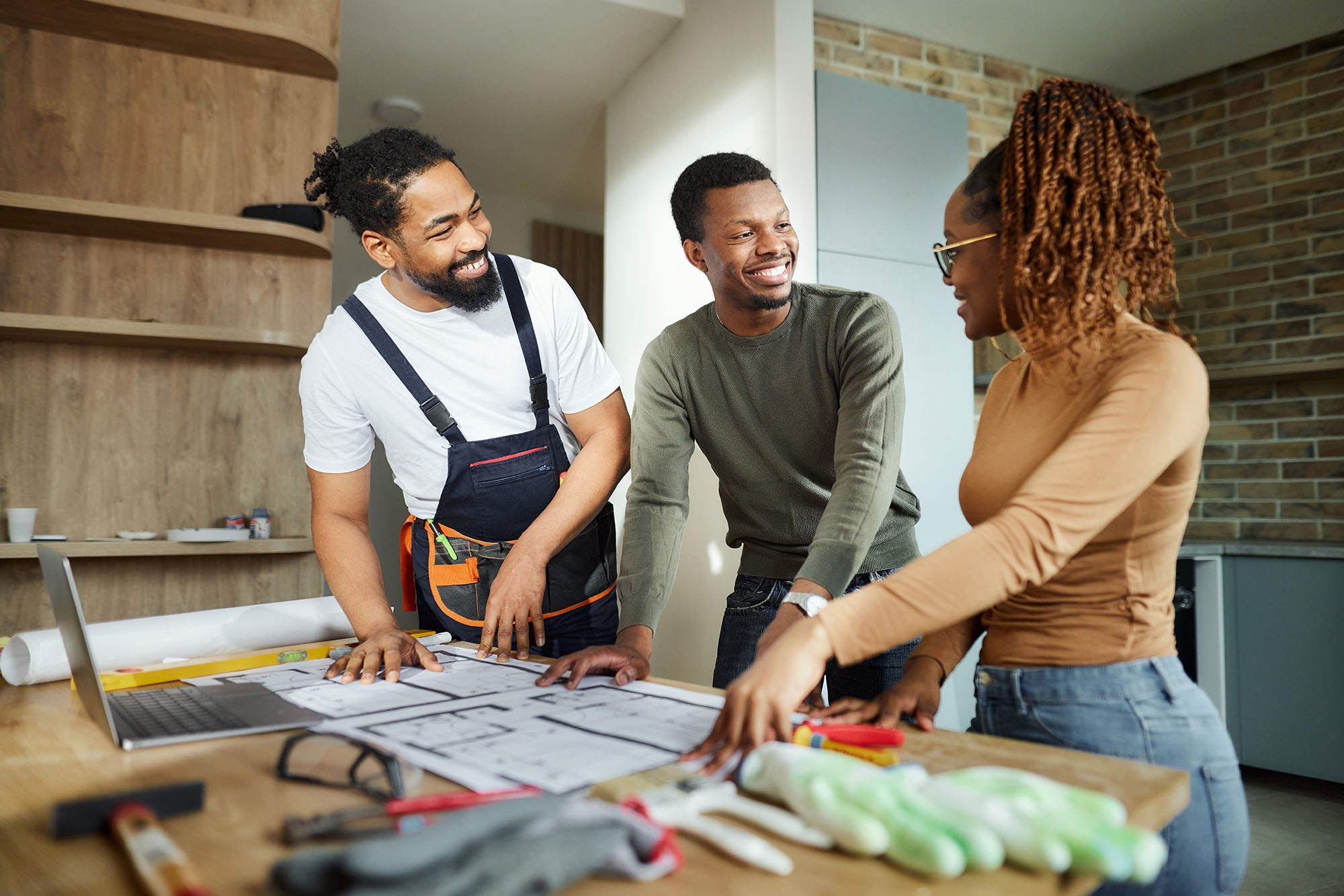 A group of people reviewing a house’s floor plan and smiling about their DIY home renovation ideas.