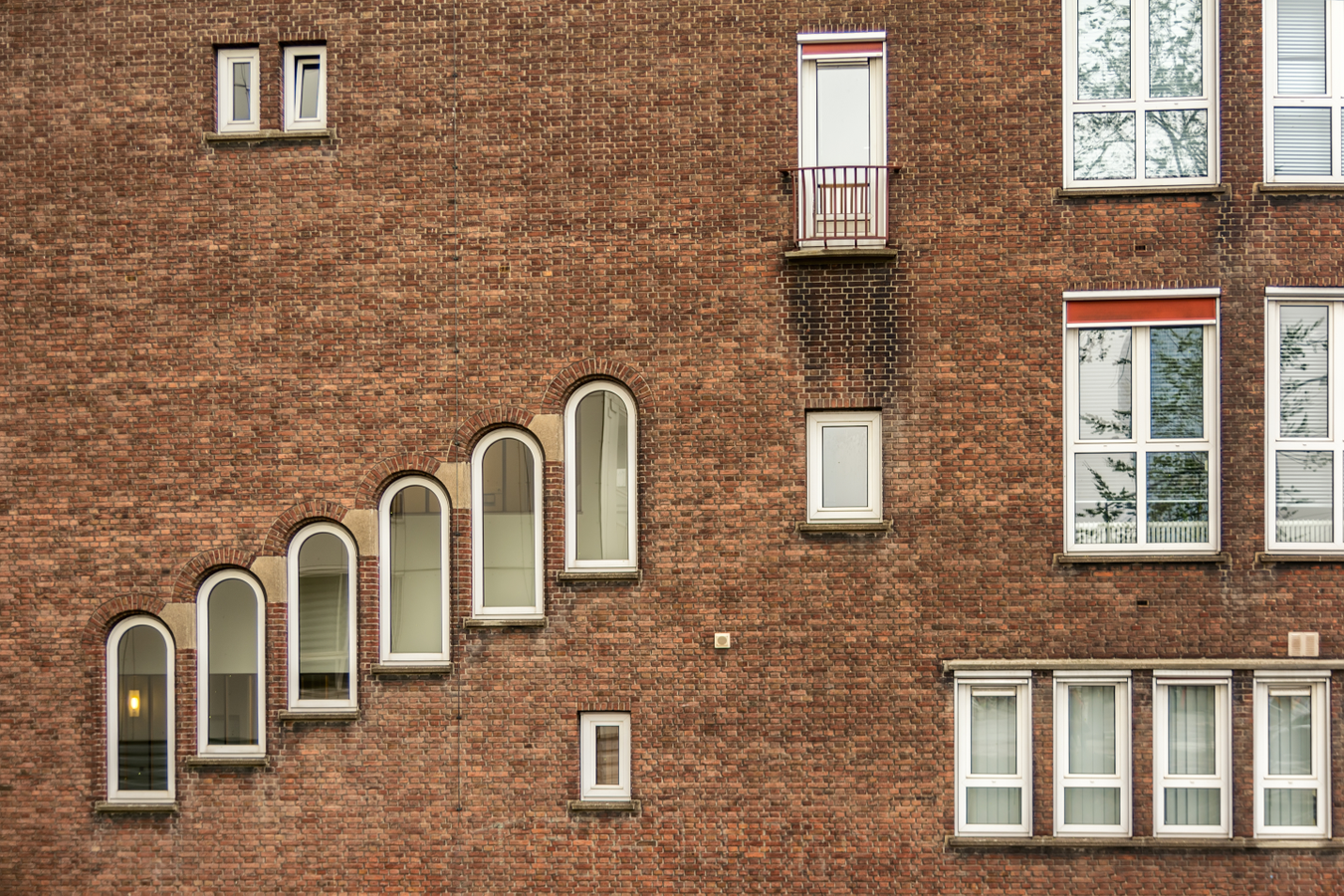 side of a brick building with many different architectural shaped windows side of a brick building with many different architectural shaped windows
