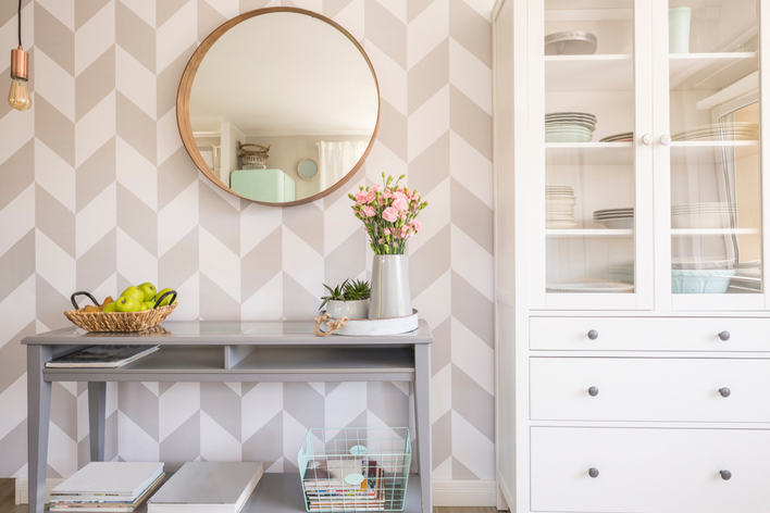 Hallway in a home with patterned wallpaper and a white cabinet