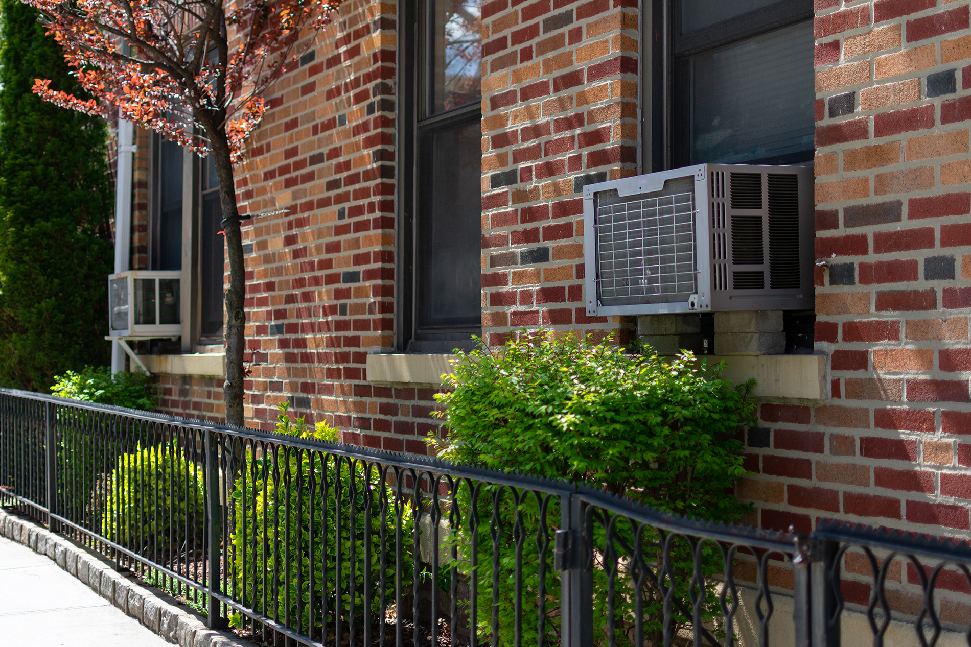 Brick home exterior with an air conditioner window unit protruding from a double-hung style window