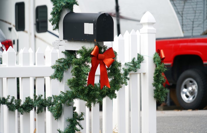 White picket fence and mailbox decorated with wreath and bow 