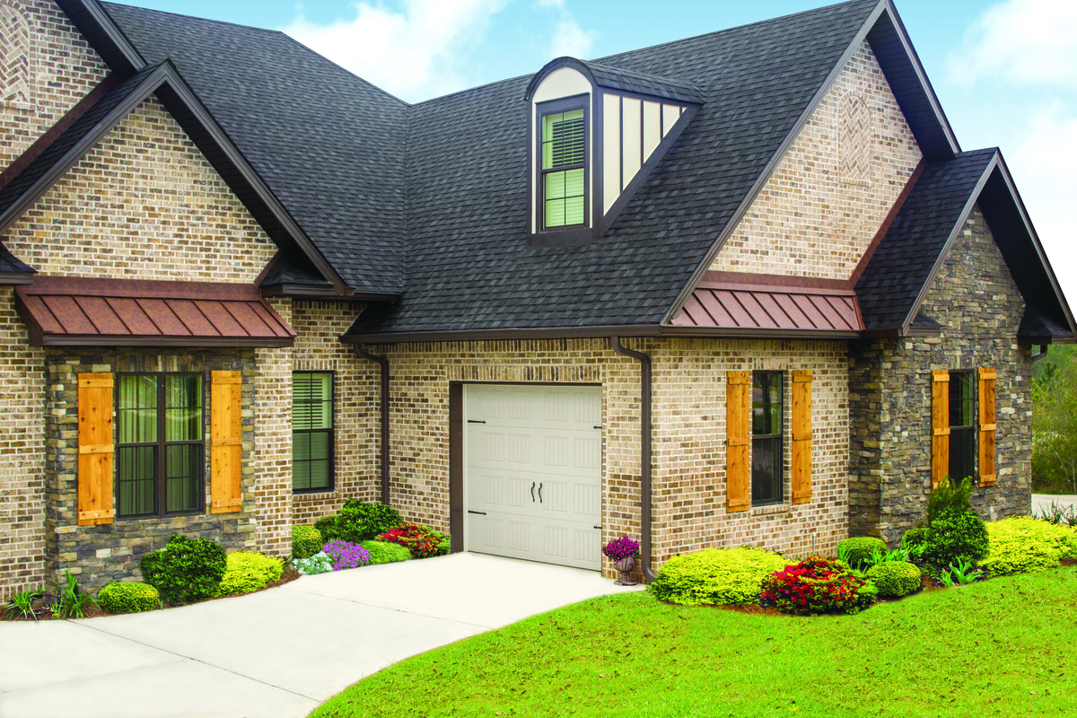 Almond short panel residential garage door installed on a brick home