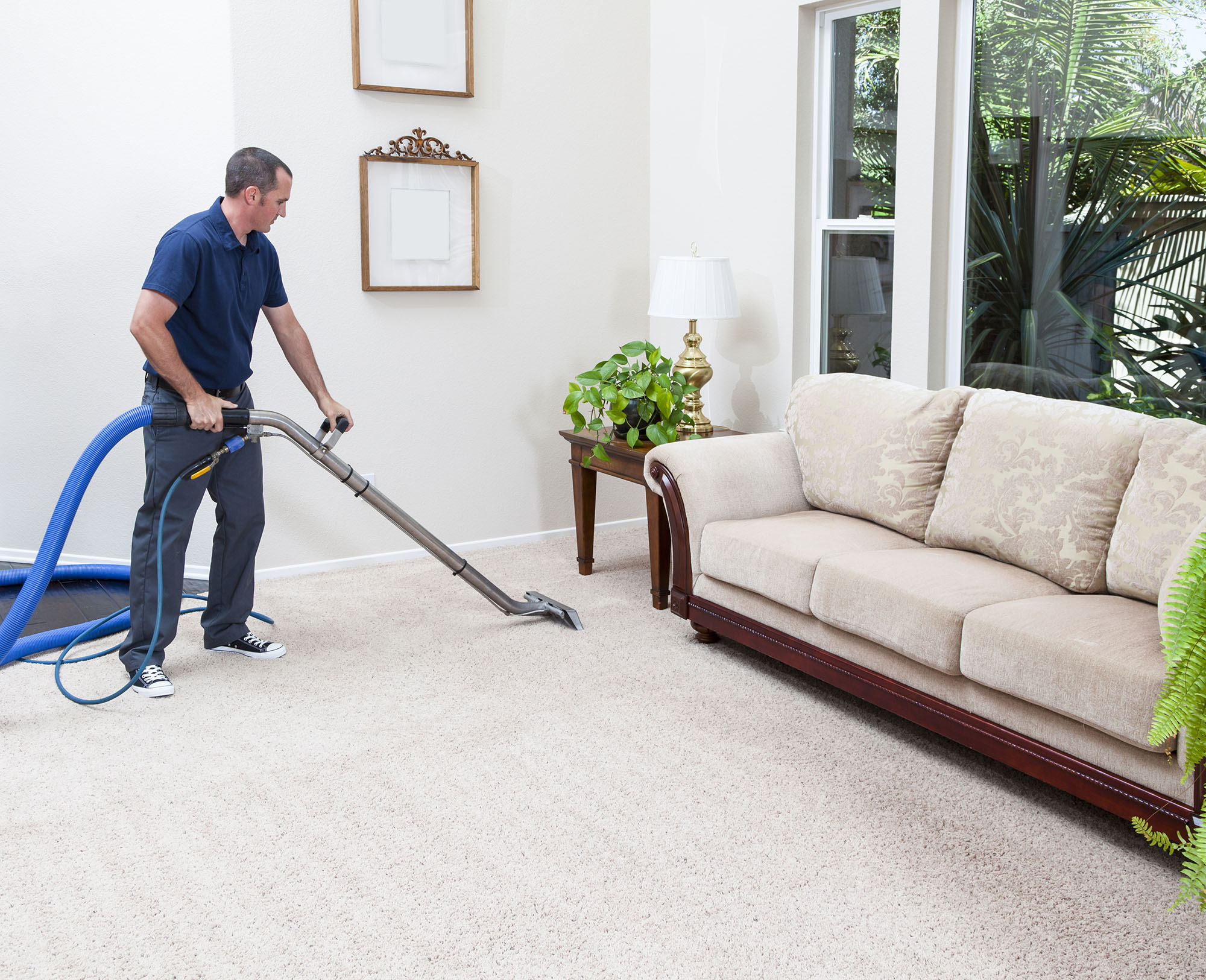 Man vacuuming the beige carpet of his old home.