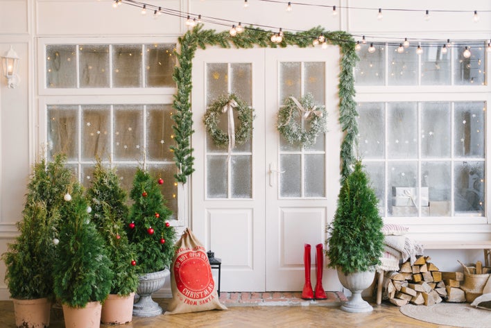 White French entry doors and windows decorated with pine garland, lights, and trees