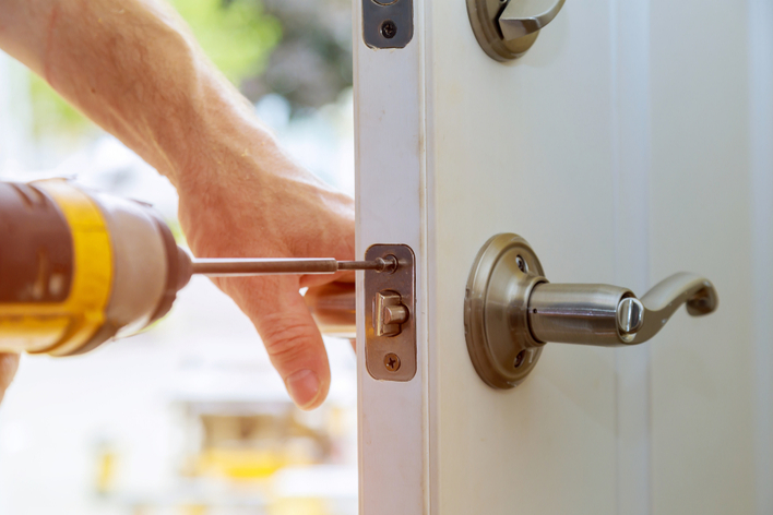 A man installing a new door handle on a white front door