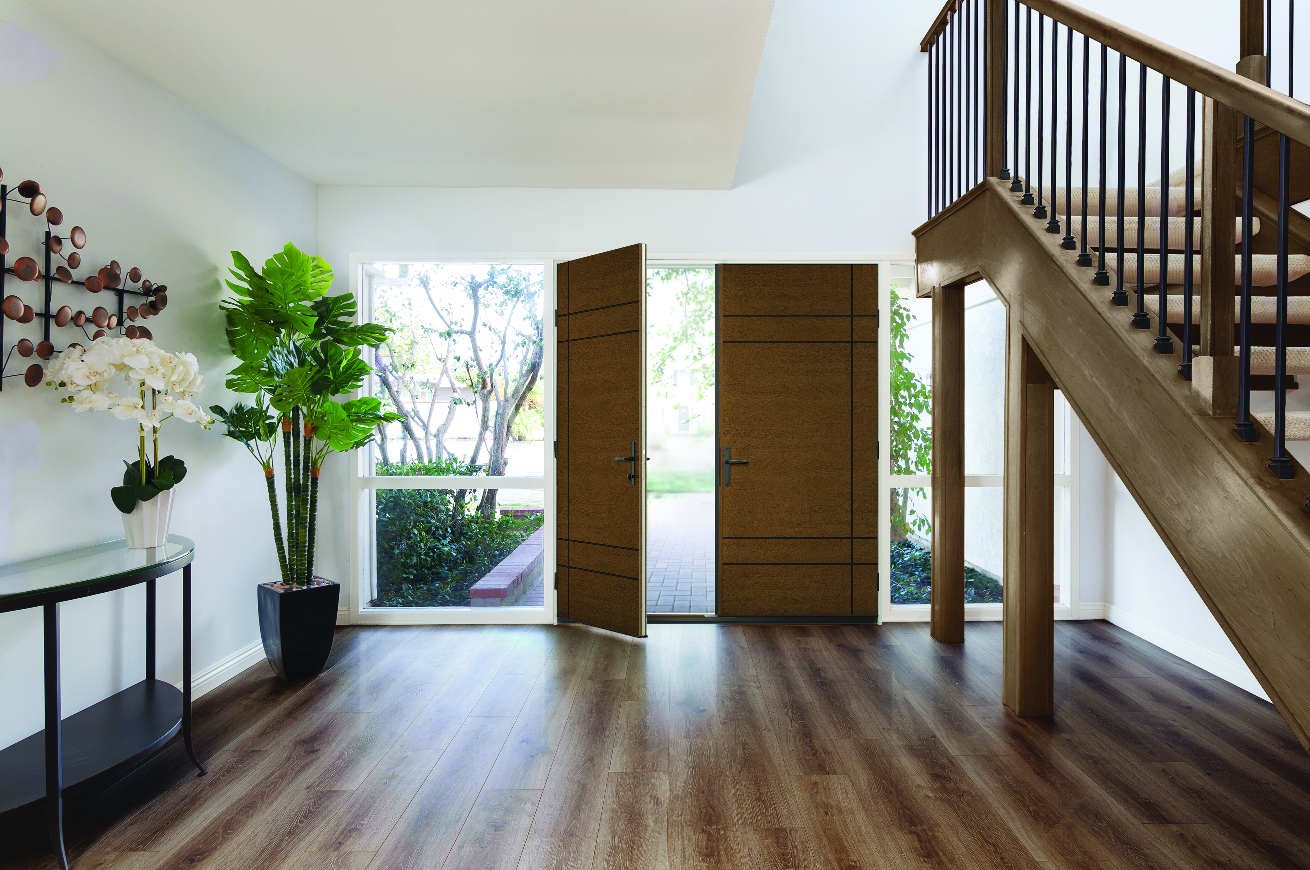 Open entry door of a home displaying the interior with house plants and staircase.