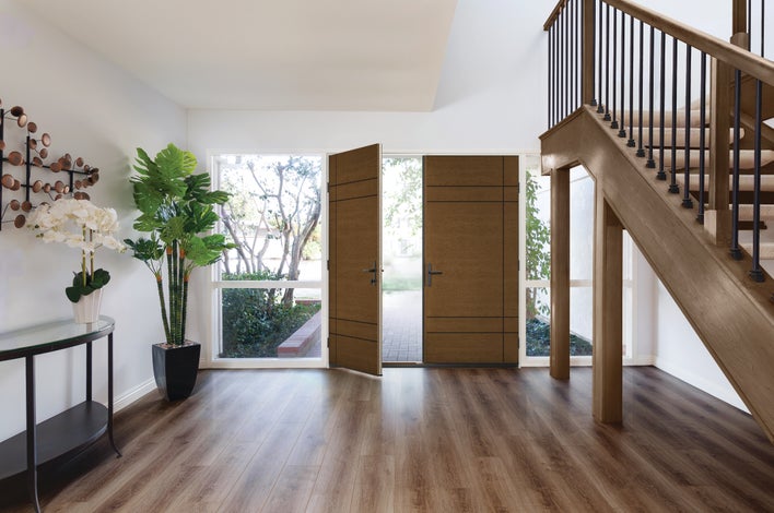 Open entry door of a home displaying the interior with house plants and staircase.