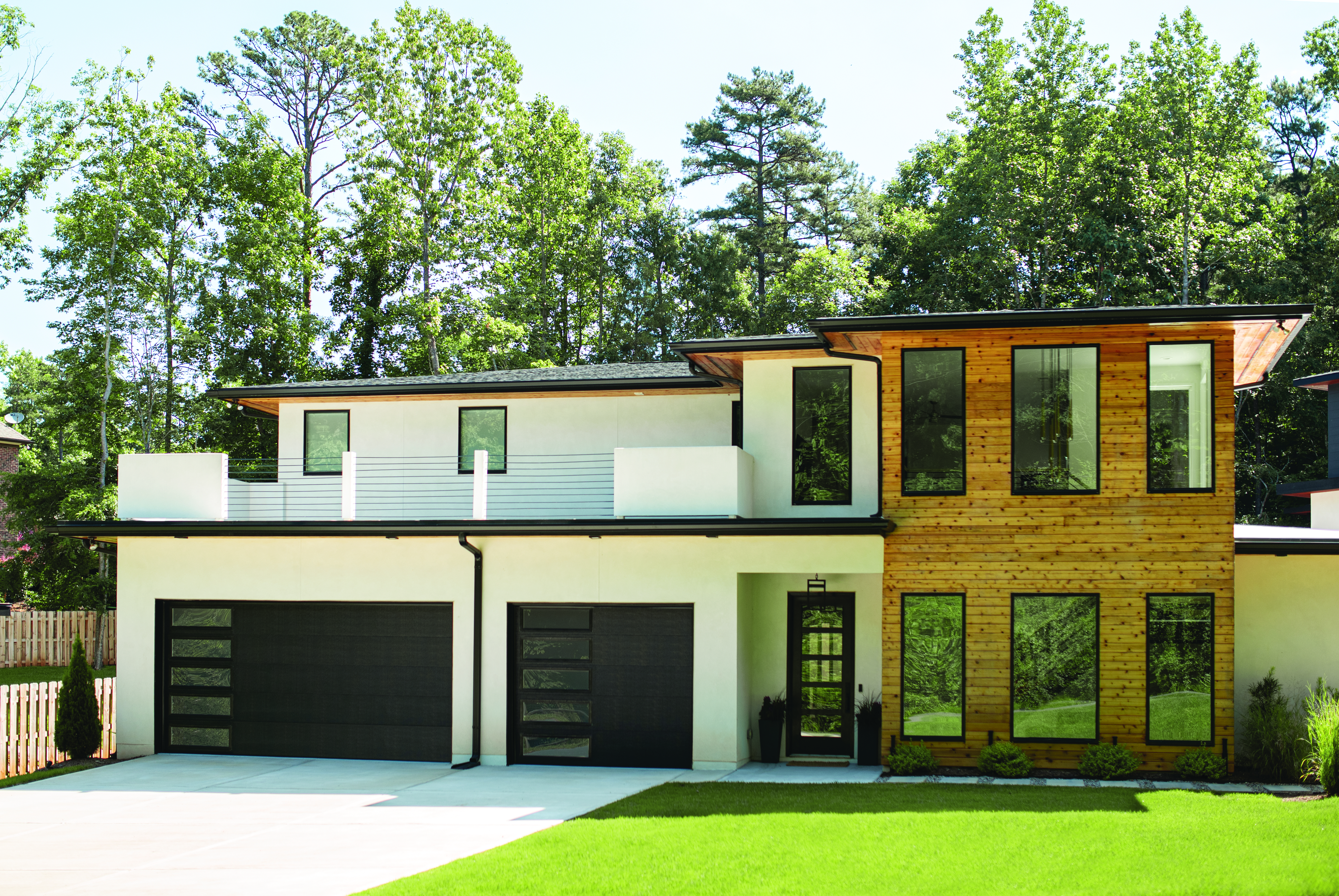 Black flush panel garage door with clear windows on a modern home