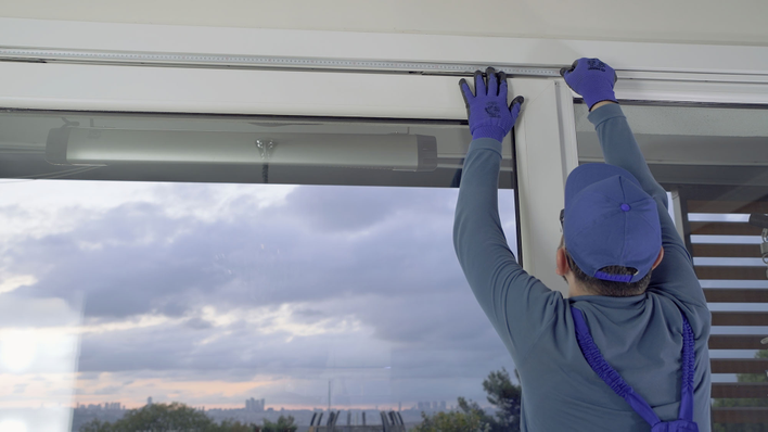 A man in a blue shirt performing professional window installation services.