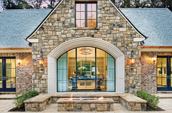 The exterior of a house with modern window design and a combination of stone and brick exterior finishes.