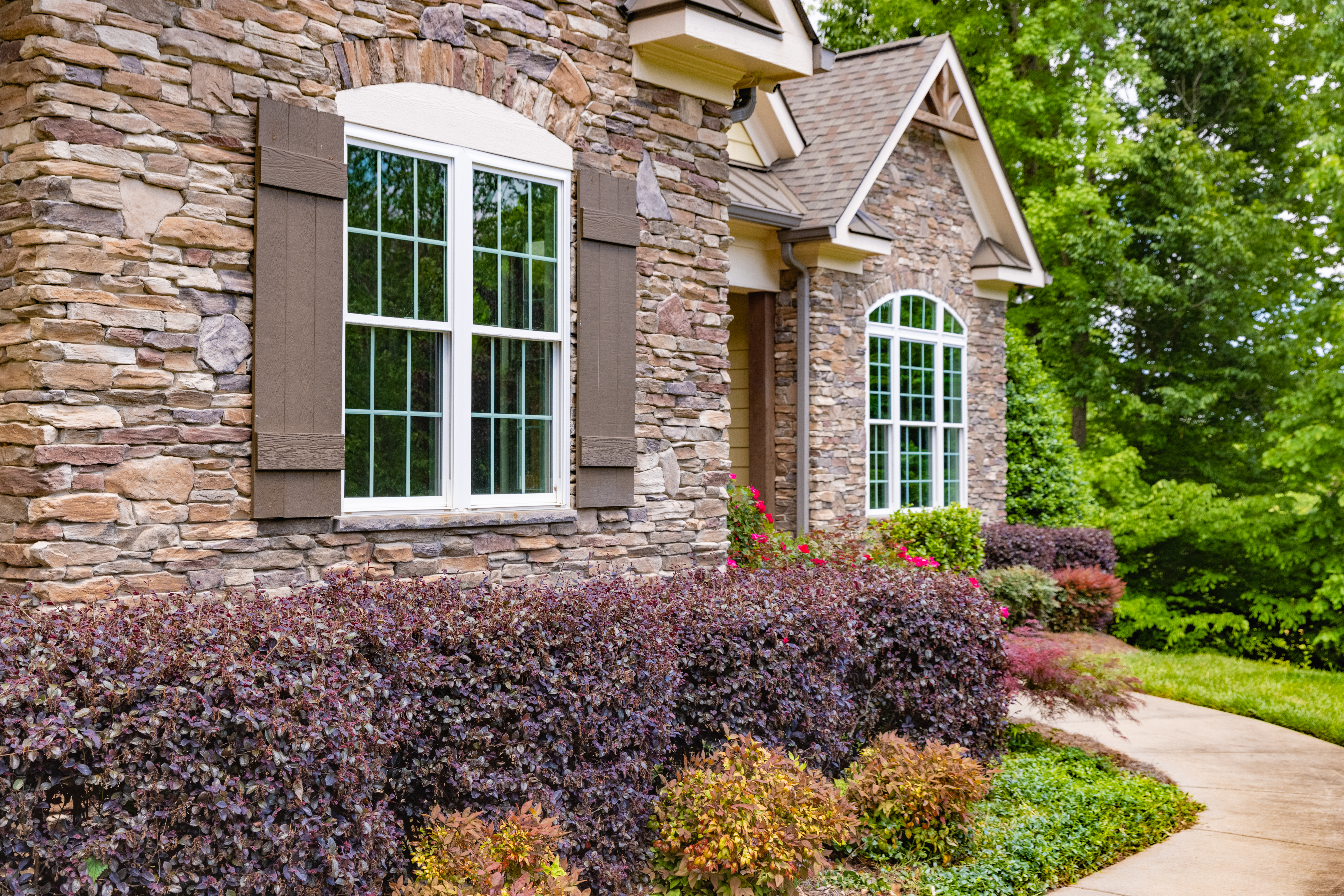 Brick home insulated with energy-efficient windows surrounded by shrubbery.
