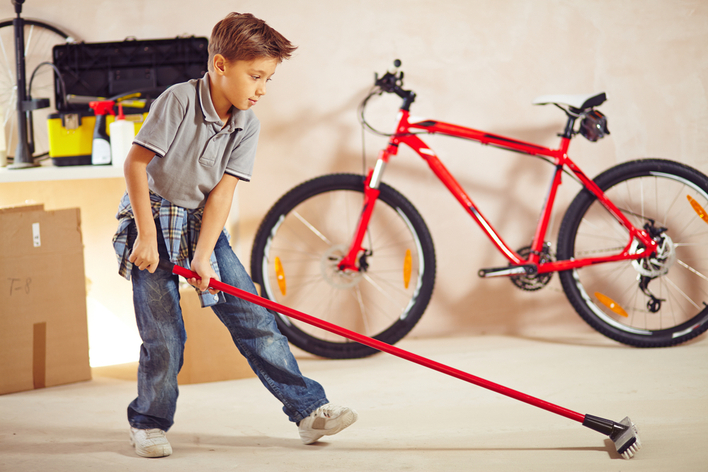 A young boy sweeping the garage floor