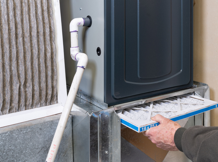 Man cleaning out the air conditioning system of a home to prep for the summer.