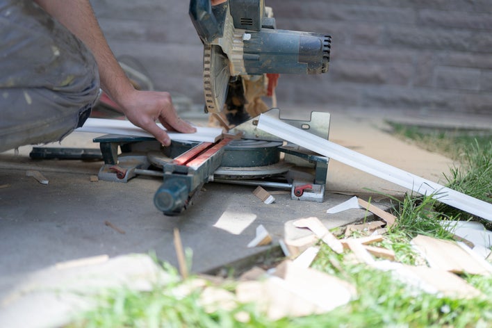 A man utilizing a circular saw to cut wood outside.