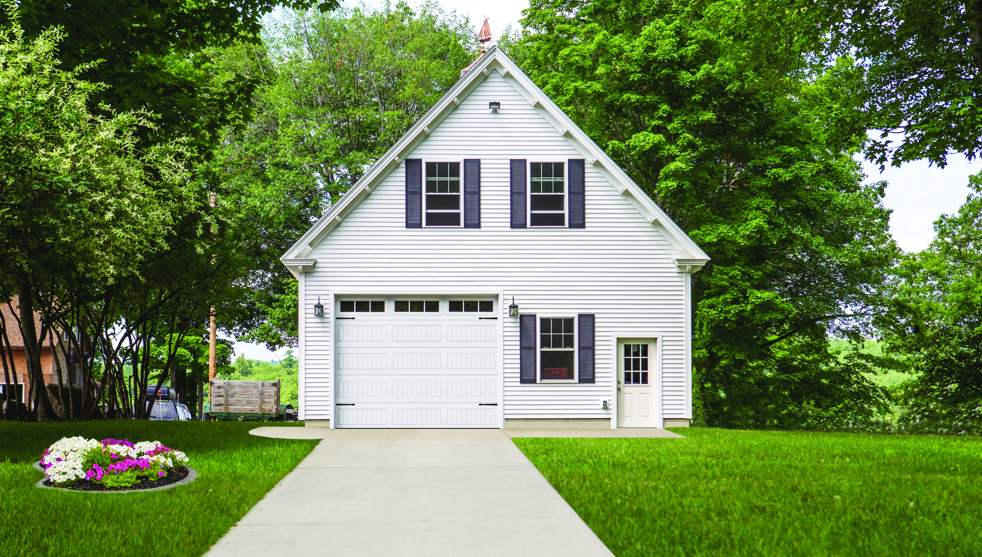 White garage door with vertical long panels and stockbridge windows on a white two-story house