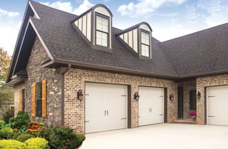 Almond sonoma panel residential garage door installed in a brick home