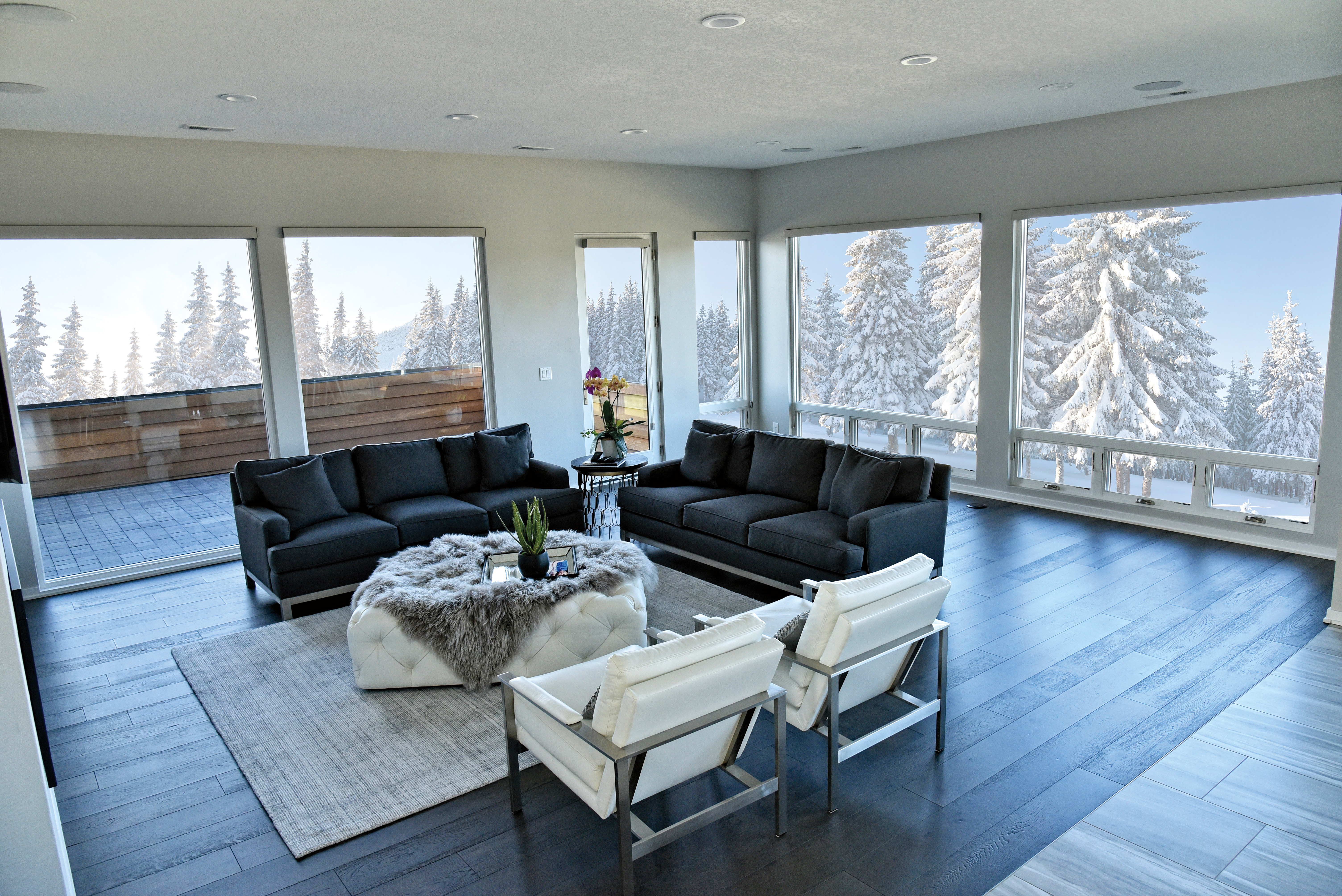 White interior wood-clad casement & awning windows in a spacious living room with snow-covered trees outside