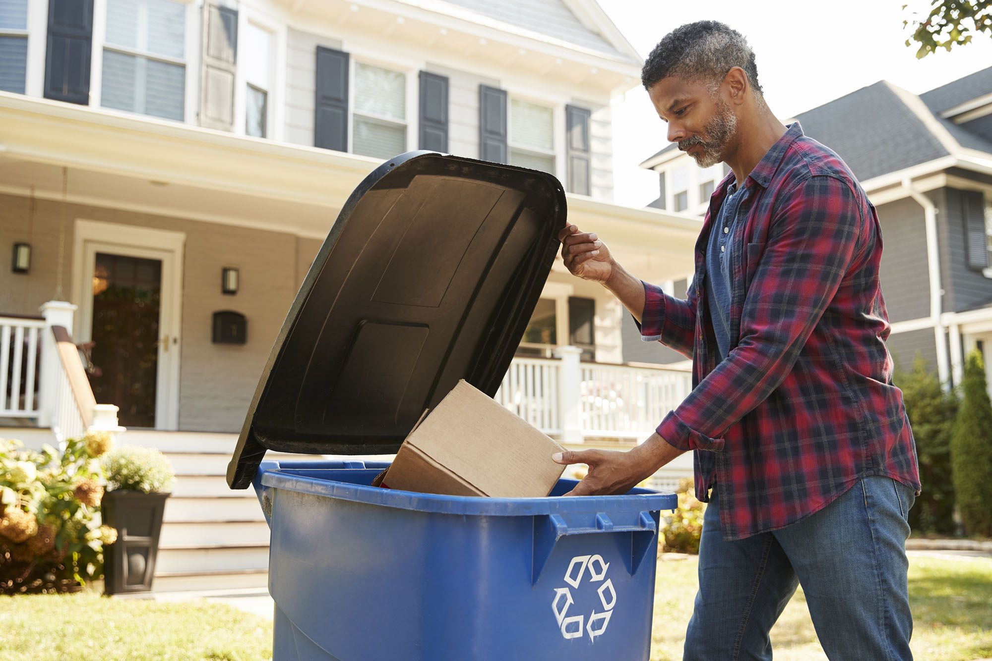 A man recycling a cardboard box to reduce his carbon footprint.