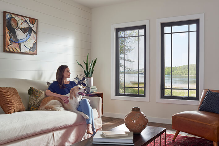 Woman sitting on a couch with her dog looking out of a casement window