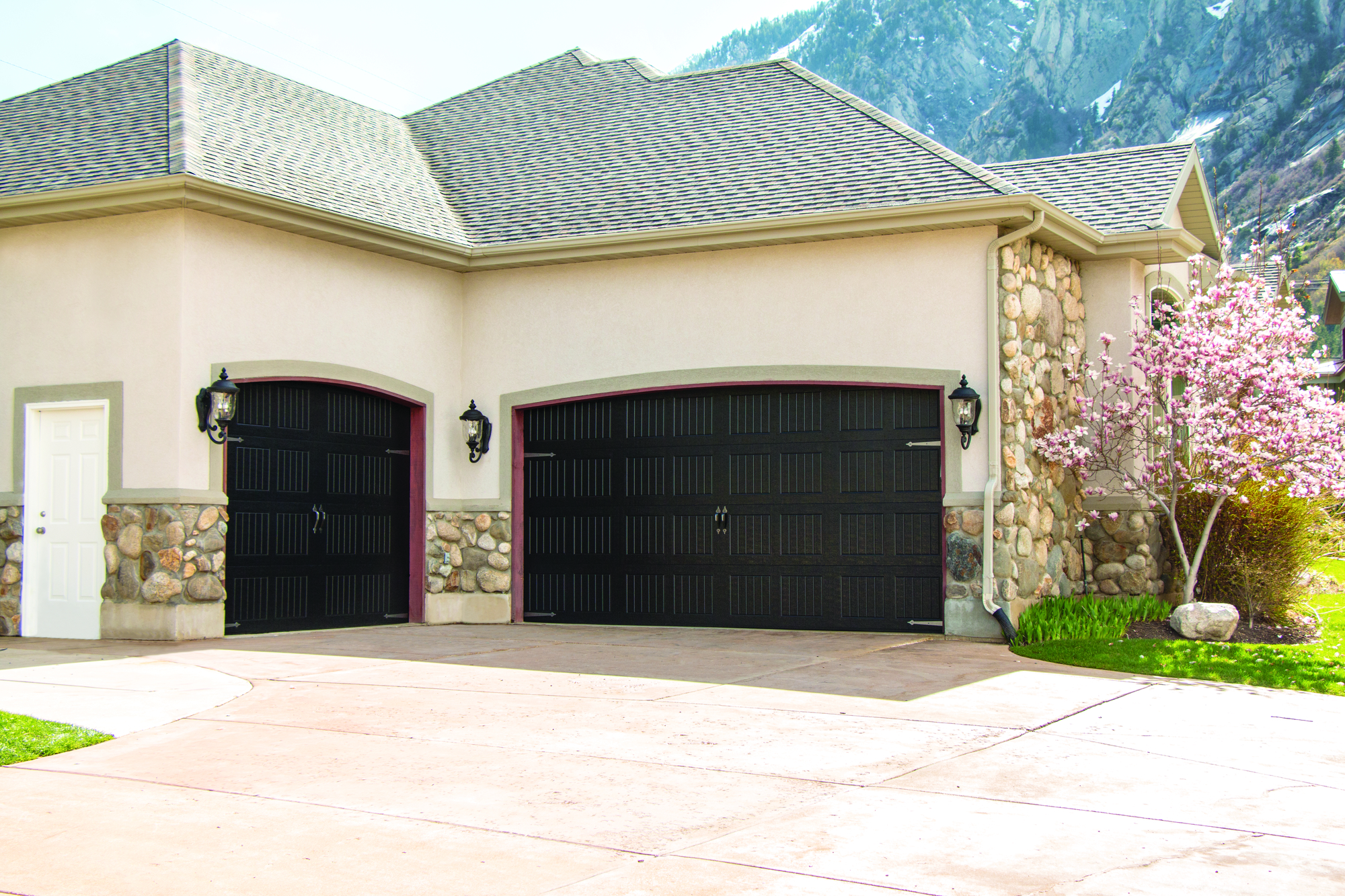 Black garage door with vertical short panels and decorative hardware