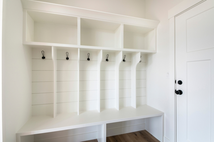 White mudroom with white door and wooden flooring