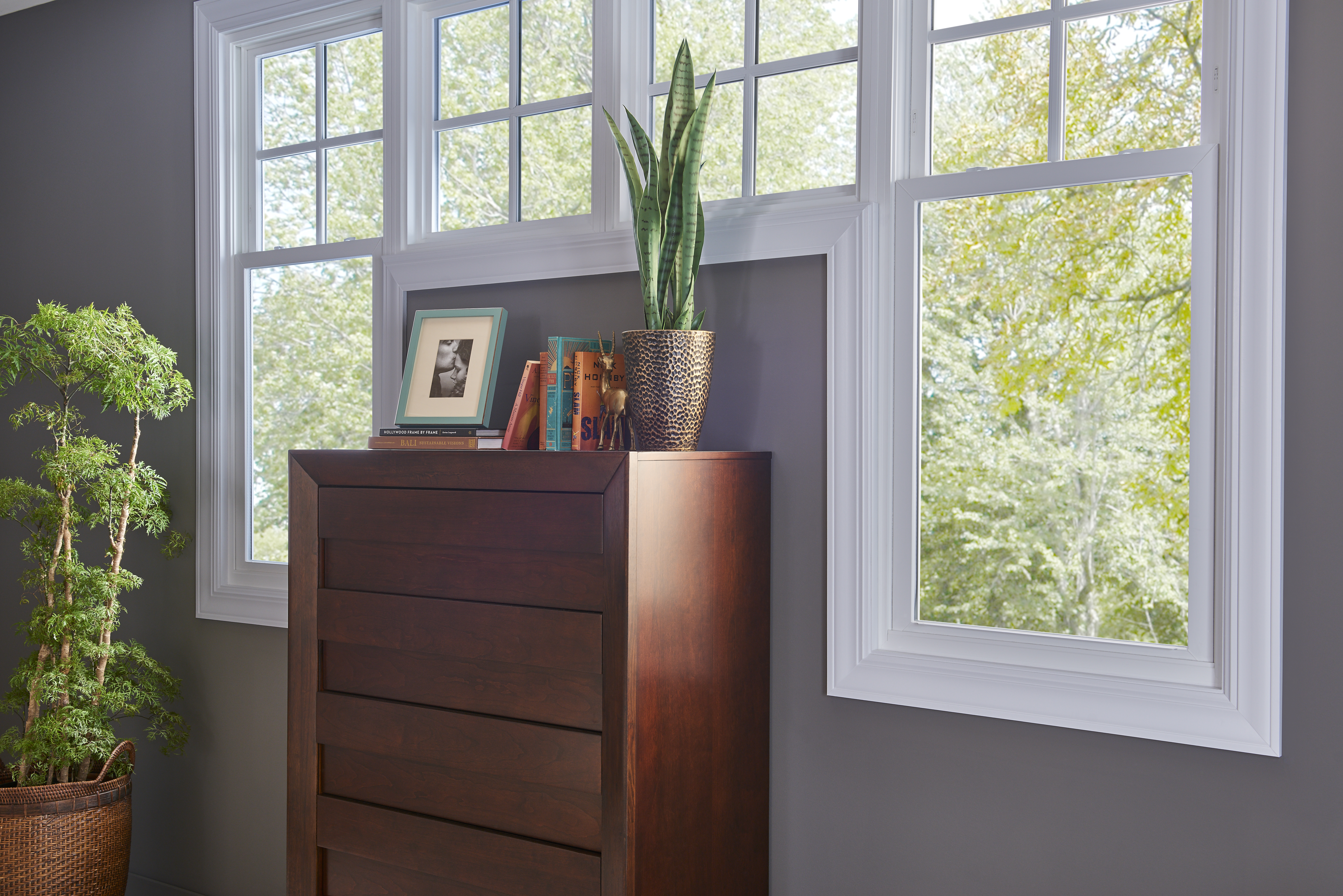 A gray wall in a house with custom double-hung windows around a dresser.