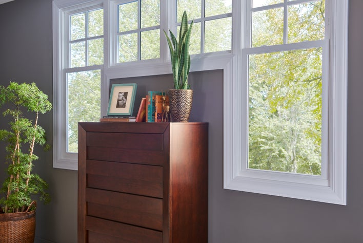 A gray wall in a house with custom double-hung windows around a dresser.