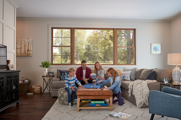 Happy family in home playing a board game seated in front of large energy-efficient windows.