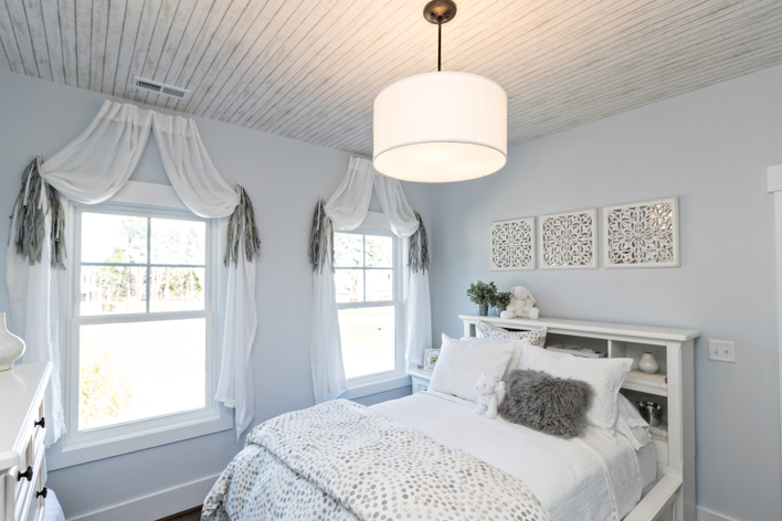 Interior of a small home bedroom with custom double-hung windows.