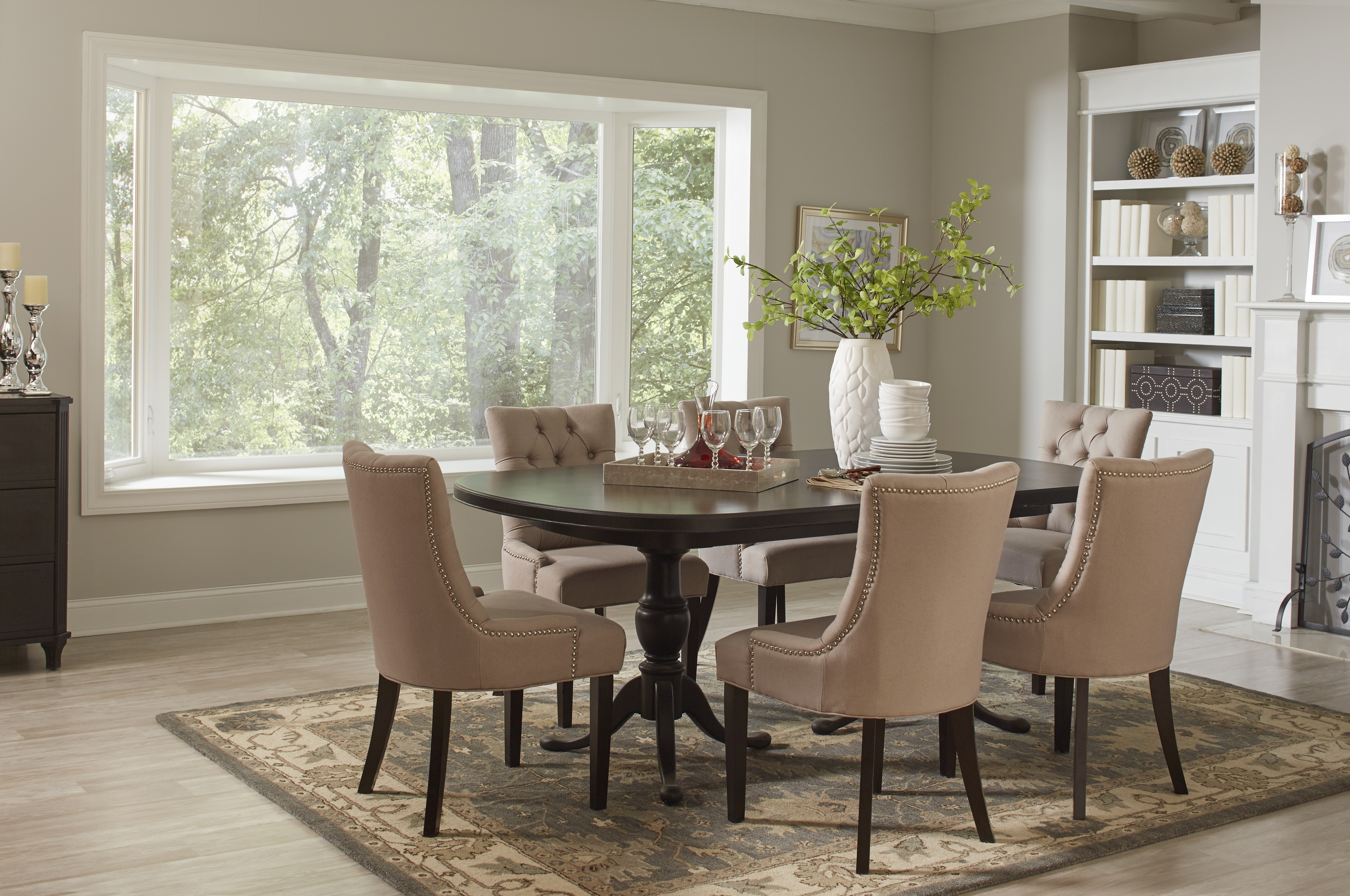 A traditional dining room with a modern bay window with a wooded view. 