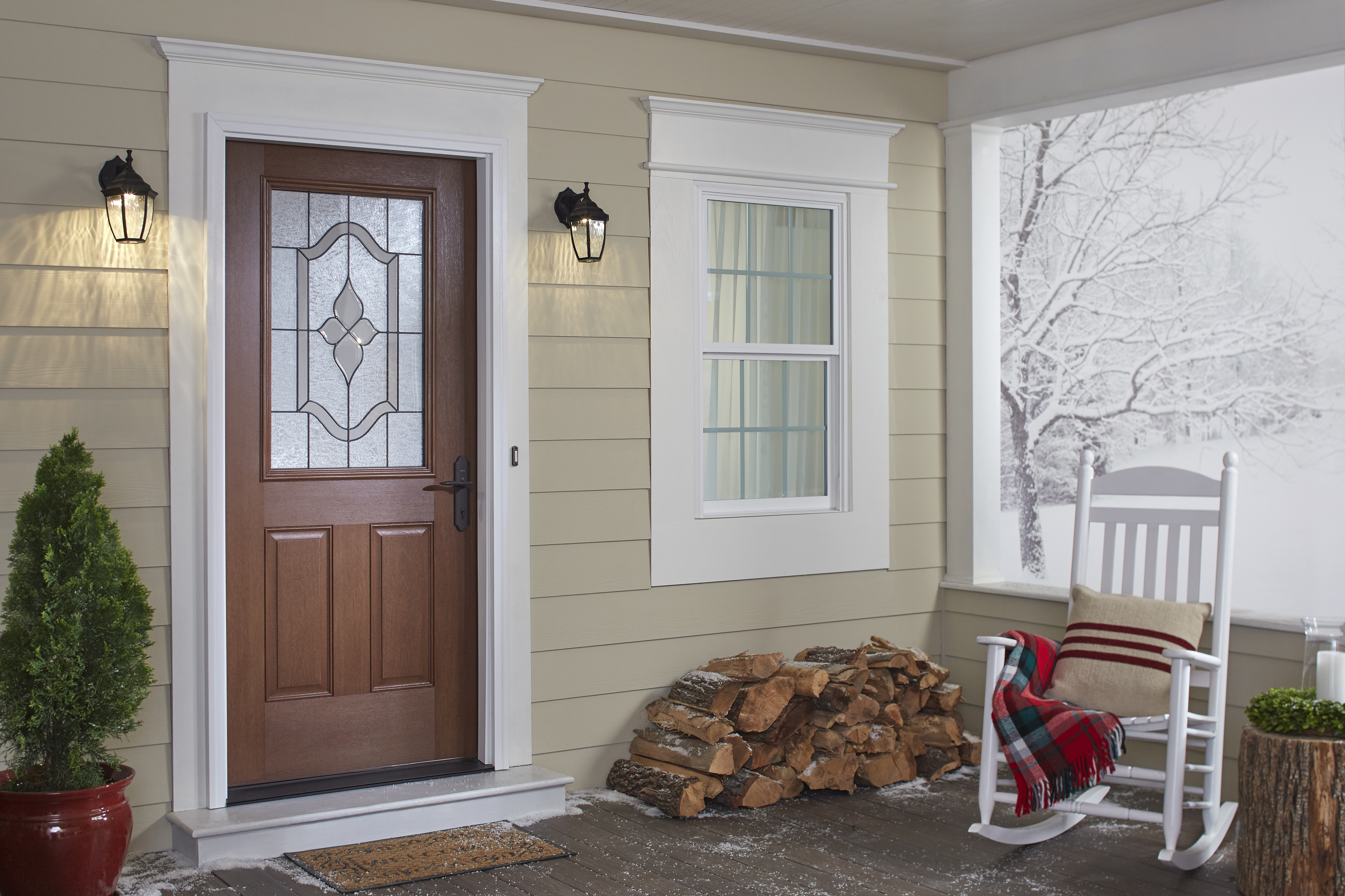A front porch with a rocking chair, a stack of wood, and snow in the background