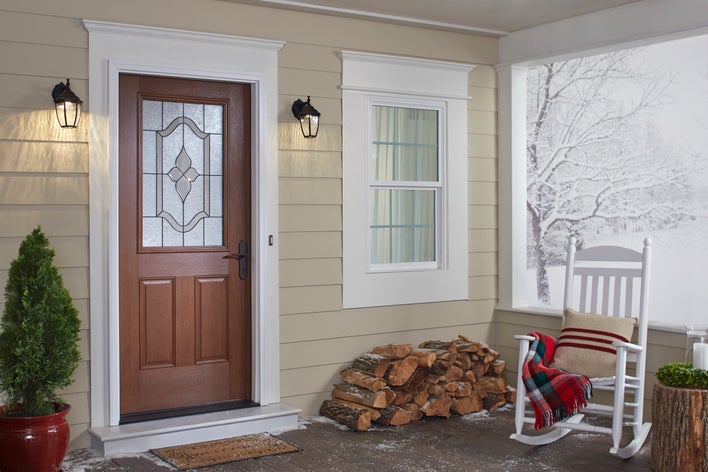 A front porch with a rocking chair, a stack of wood, and snow in the background A front porch with a rocking chair, a stack of wood, and snow in the background