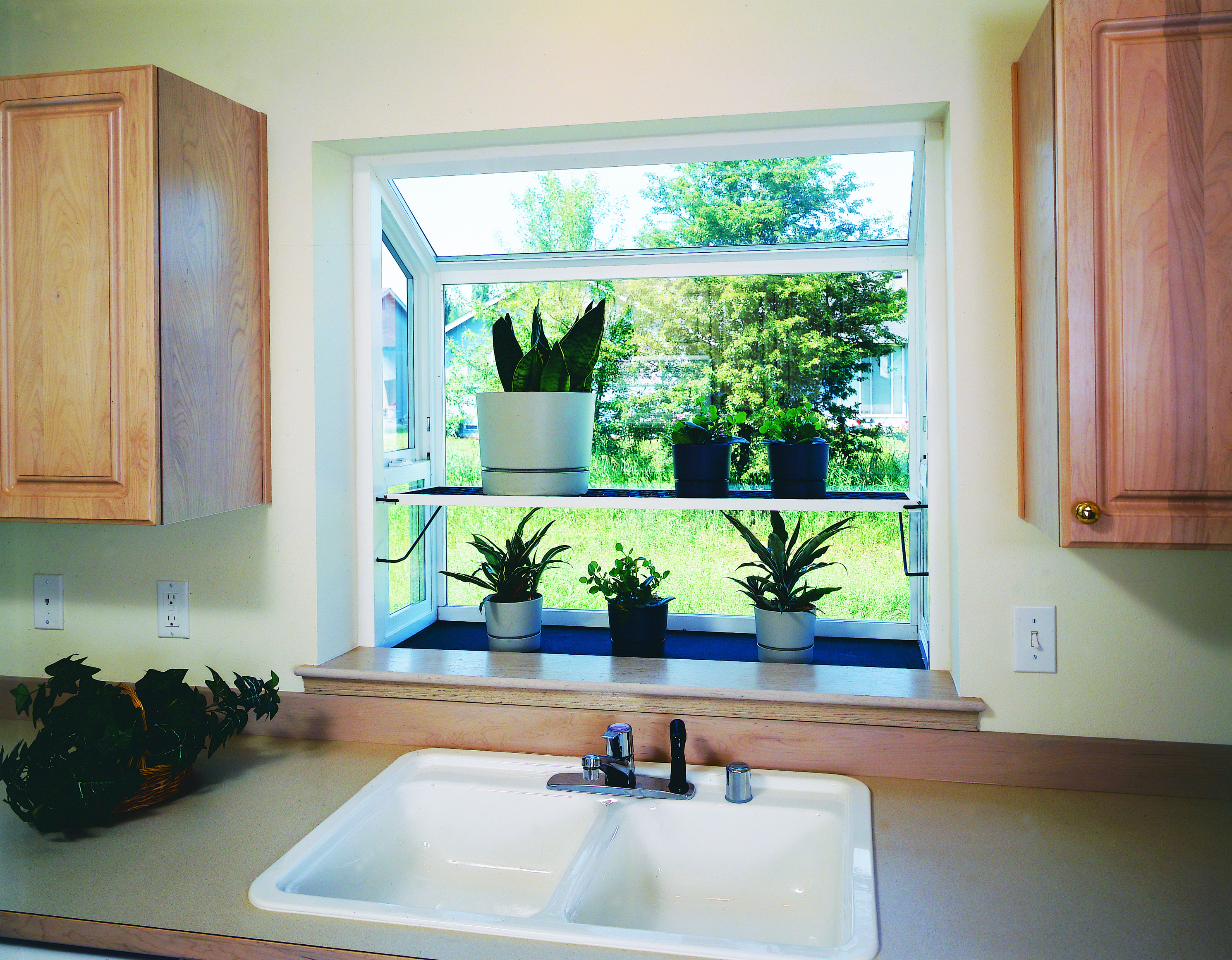 A garden window containing an herb garden above a kitchen sink in a modern home.