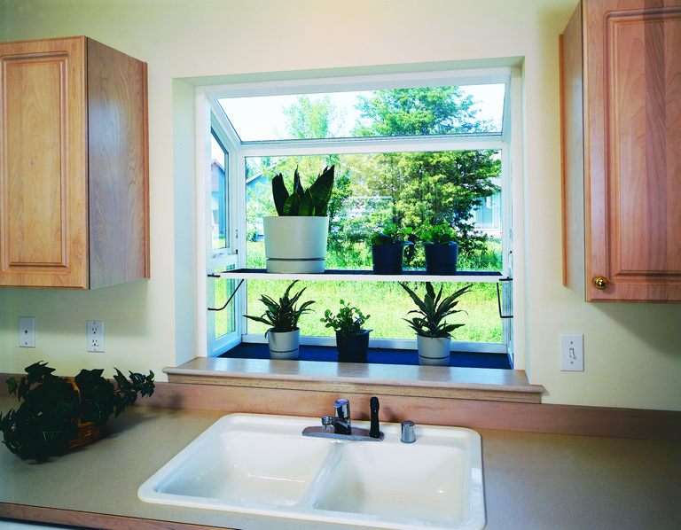 A garden window containing an herb garden above a kitchen sink in a modern home.