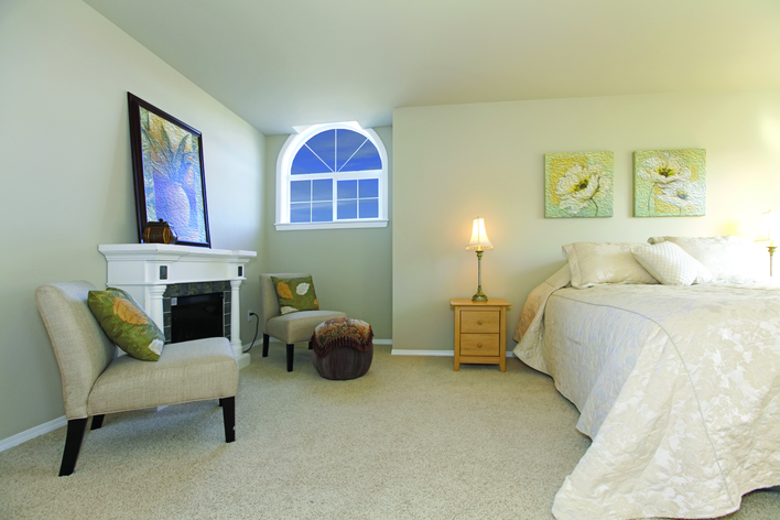Large bedroom with white bed and fireplace with custom architectural shape windows and sliding windows.