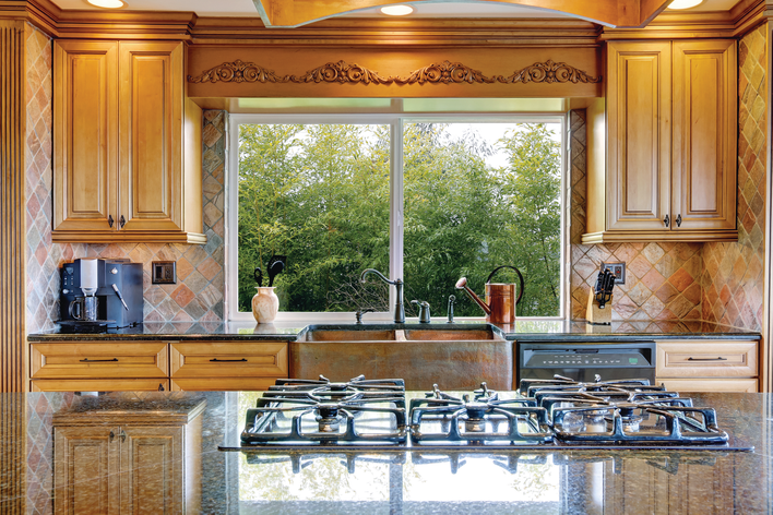 Custom sliding windows within the kitchen of a home above the sink.