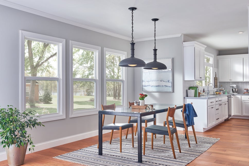 A kitchen with gray walls, 3 windows and a dinner table