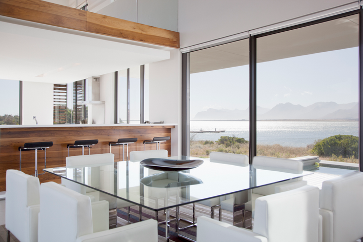 A modern home with clean lines, an open floorplan, and large modern windows with a view of mountains and a large body of water.