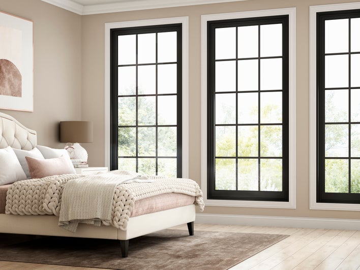 Bed beside three tall windows.