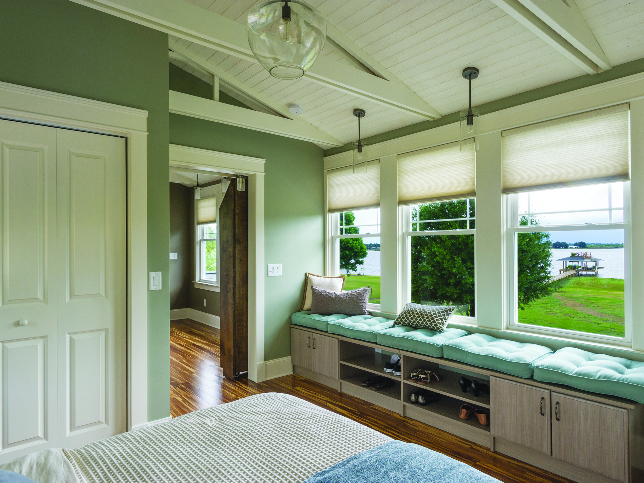 A bedroom with several single-hung vinyl windows overlooking a nearby body of water.