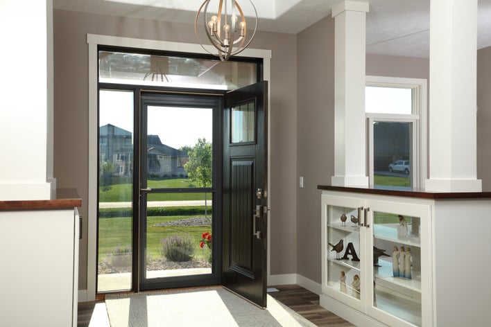 An entryway protected by a screen door while the black woodgrain entry door stands open