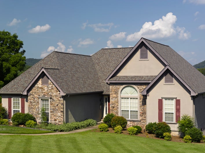 A beautiful house with stacked stone details, architectural-shaped windows, and a pristine gabled roof.