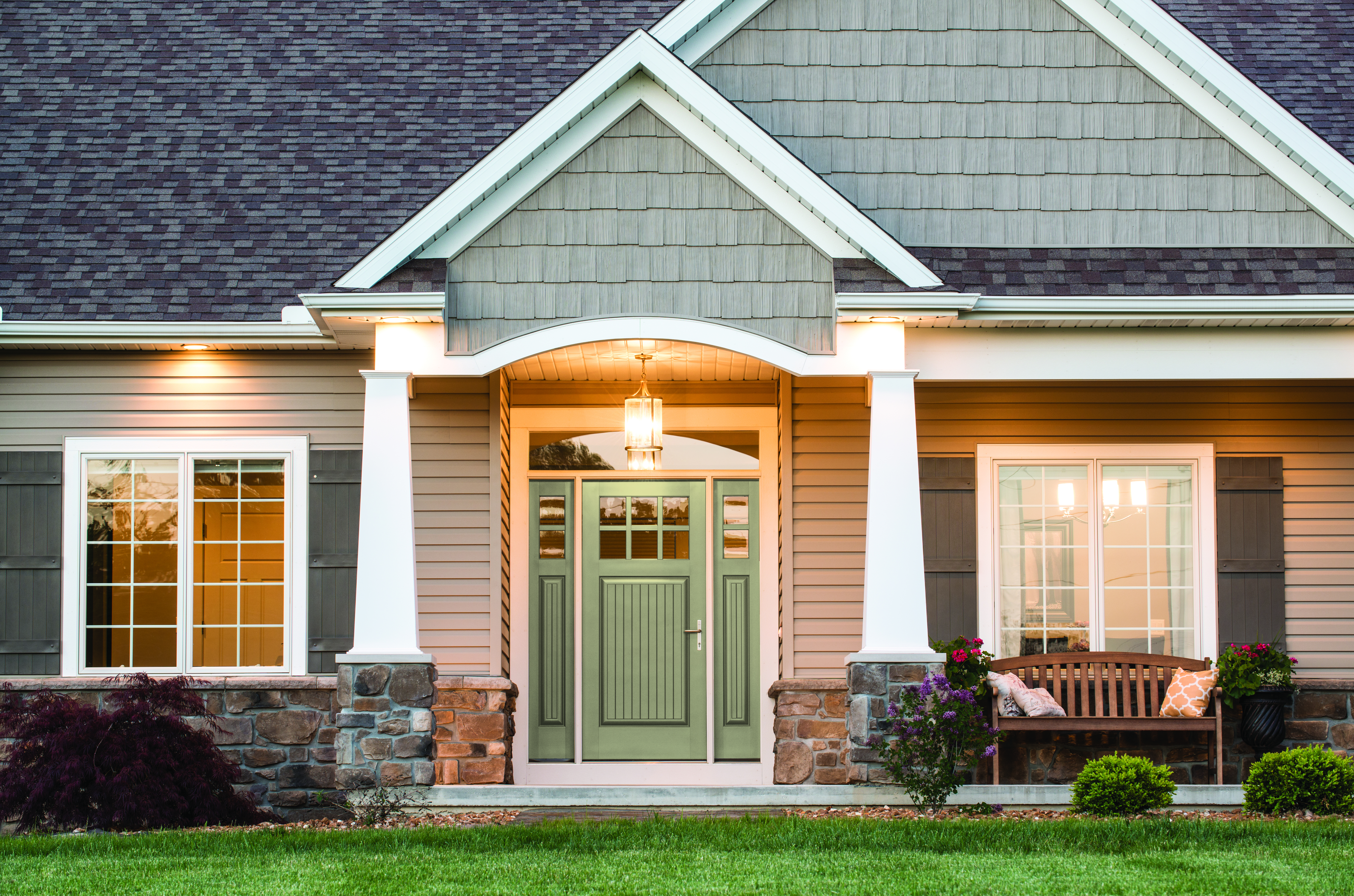 Canvas grain entry door installed on a gray home with a wooden bench on the front porch.