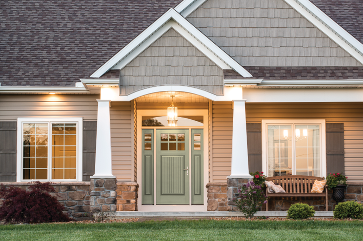 Canvas grain entry door installed on a gray home with a wooden bench on the front porch.