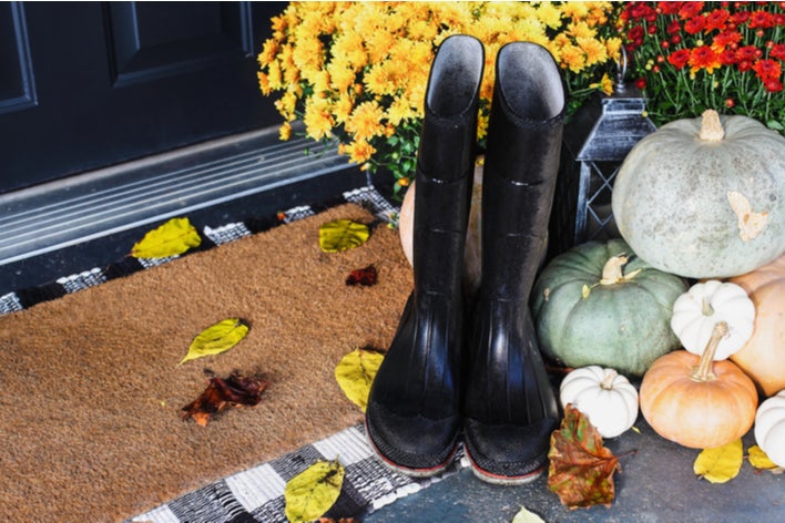 An idea for decorating a front porch for fall is rain boots and mums