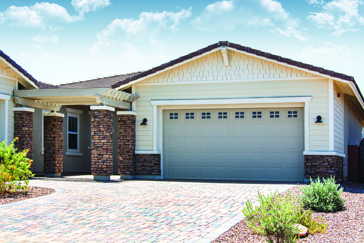 Tan short panel garage door with stockton windows installed on a residential home
