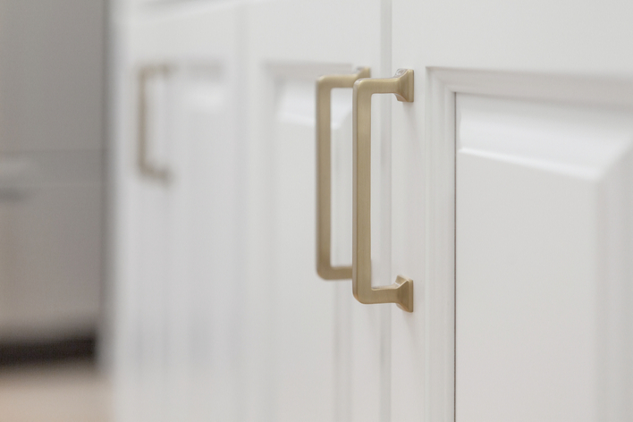 Close-up image of gold handles on white cabinets