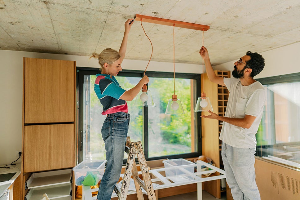 A couple removing a light fixture from their ceiling