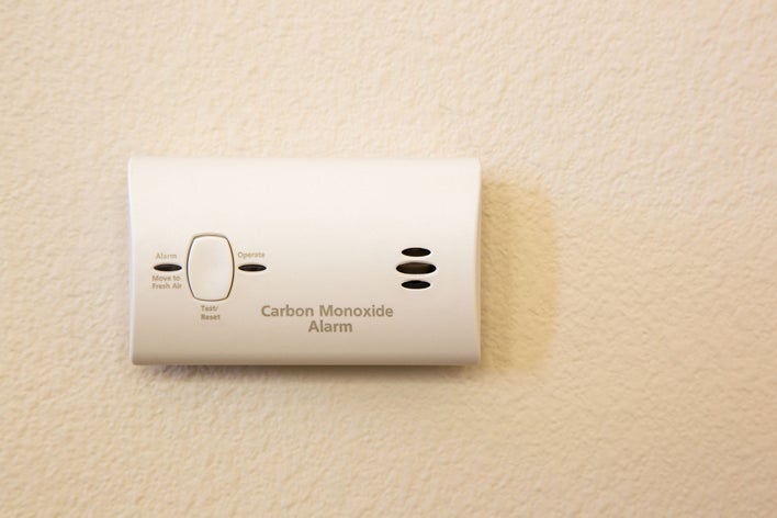 A close-up of a carbon monoxide alarm mounted on a wall.