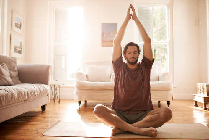 A man doing yoga with the benefit of two natural light windows. 